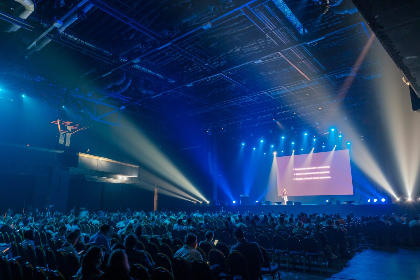 Audience sitting in front of stage with screen